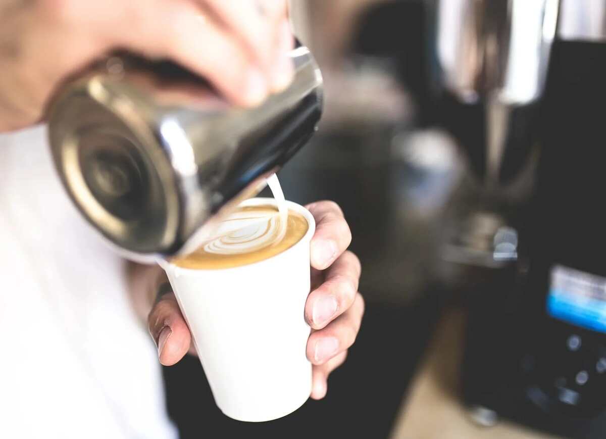 Milk being poured into a takeaway coffee.